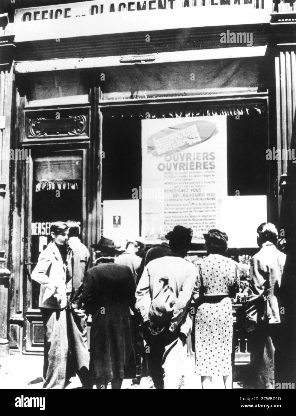 Citizens of Paris outside a German labour recruitment office, 1940-1944. Faced with a decline in the supply of forced labour from occupied Poland and Russia, the Nazis demanded France send 250,000 labourers to Germany by the end of 1942. The Germans agreed to repatriate one French prisoner of war for every three volunteer labourers. But the number of volunteers was insufficient and a form of conscription was introduced. By the time France was liberated an estimated 650,000 men and 44,000 women had been sent to work in Germany. The photographer is unknown. Stock Photo