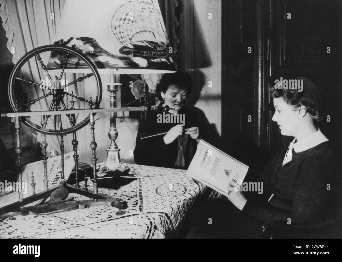 Two women at home, France, 1939. The woman in the foreground is reading a copy of Le Livre Jaune Francais, a book published by the French Foreign Ministry relating to diplomatic negotiations between Britain, France, Poland and Germany before the outbreak of World War II. The photographer is unknown. Stock Photo