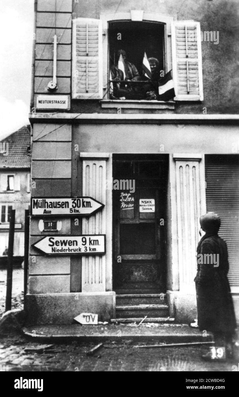 Liberation of Alsace-Lorraine, 1944-1945. People waving French tricolours from an upstairs window of a house on the road to Mulhouse. The photographer is unknown. Stock Photo