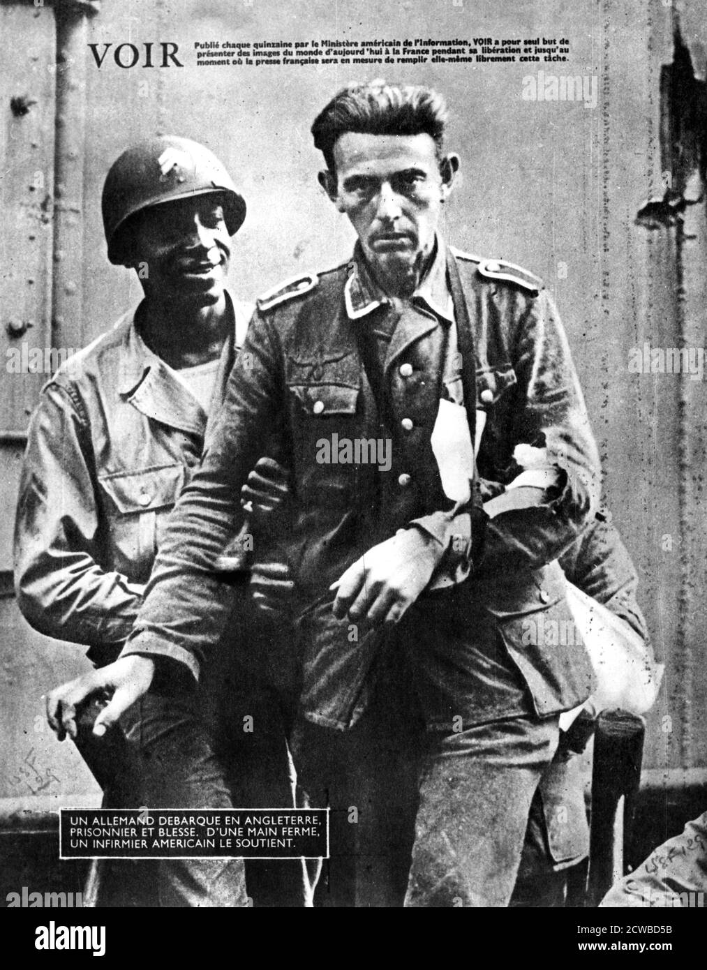 German prisoner of war arriving in England, escorted by an American soldier, 1944. Photograph from Voir magazine an American French language publication. The photographer is unknown. Stock Photo