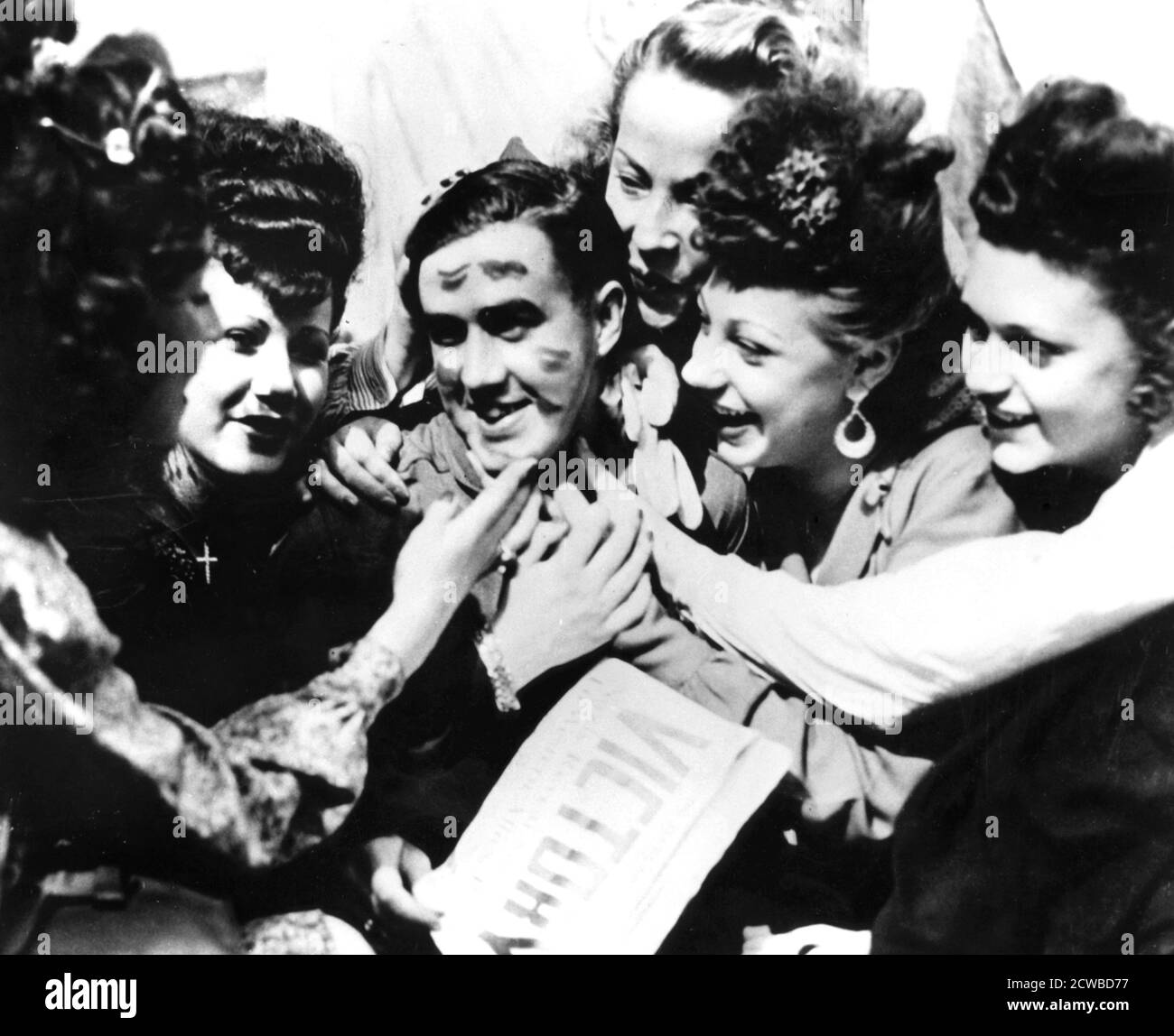 VE Day celebrations, Paris, 8 May 1945. A soldier smothered with kisses by jubilant women. The photographer is unknown. Stock Photo