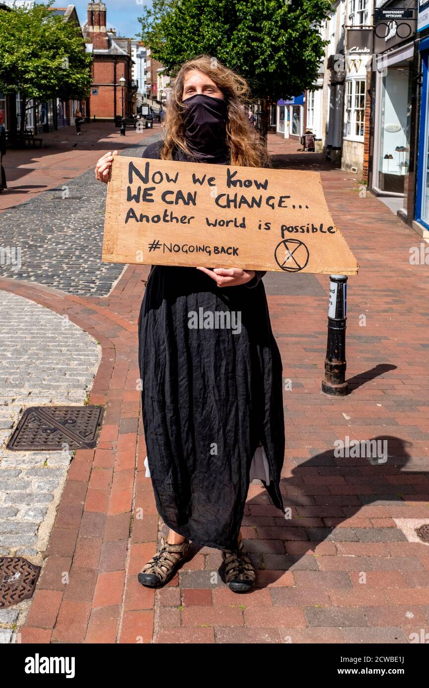 An Environmental Protester Walks Through The Streets Of Lewes Holding A Sign During The Corona Virus Pandemic, Lewes, East Sussex, UK. Stock Photo