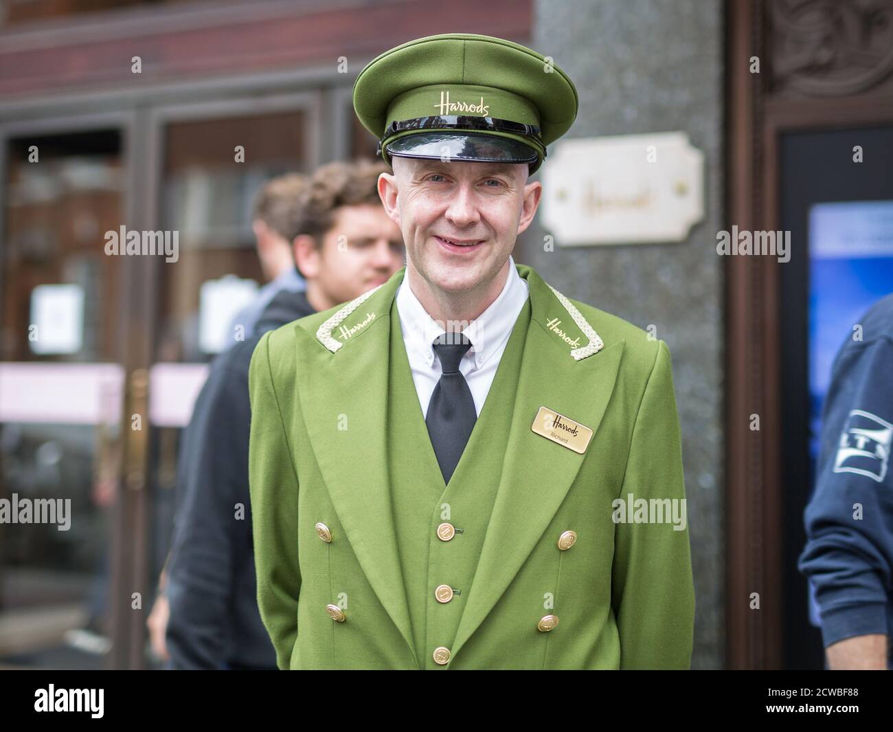 Street Photography: Portrait of Harrods Department Store Receptionist with Green Uniform and Hat in London. Stock Photo