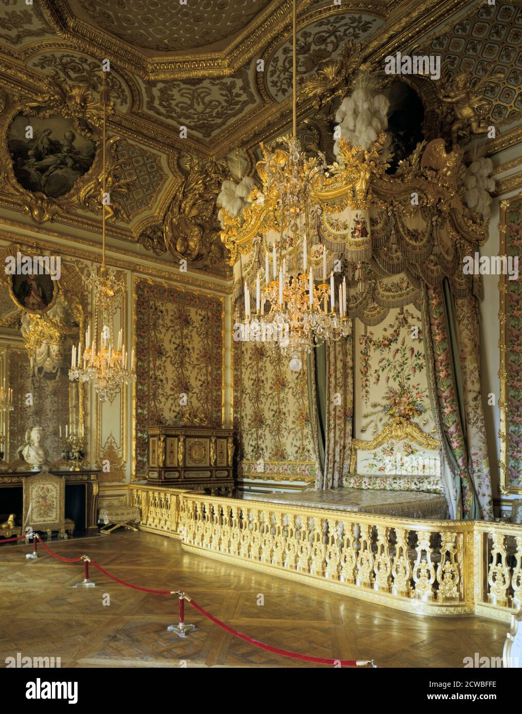 The Queen's Bedchamber, The Queen's Suite (Grand Apartment de la Reine), Chateau de Versailles, France. The Rococo-style woodwork, as well as the ceiling painting by Francois Boucher (1703-1770) were commissioned around 1730 by Louis XV in order to please his wife, Maria Leszczynska. Marie-Antoinette found this terribly old-fashioned, and decided to replace all the furnishings, notably commissioning silk hangings woven in patterns of lilacs and peacock feathers, garnishing the alcove and the enormous four-poster bed (restored in 1976). Stock Photo