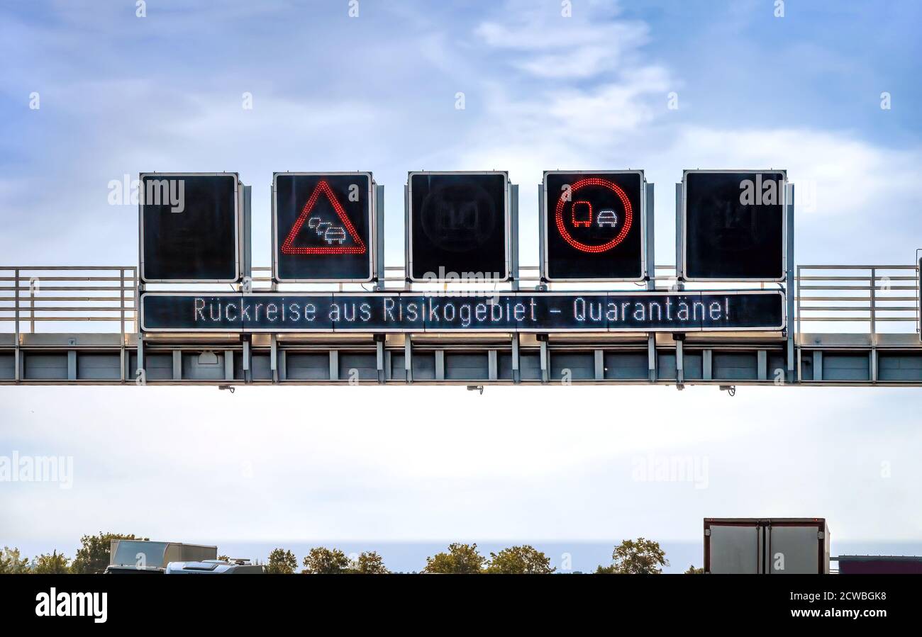 Sign gantry over the motorway that holidaymakers should quarantine themselves at home after returning home from risk areas. Stock Photo