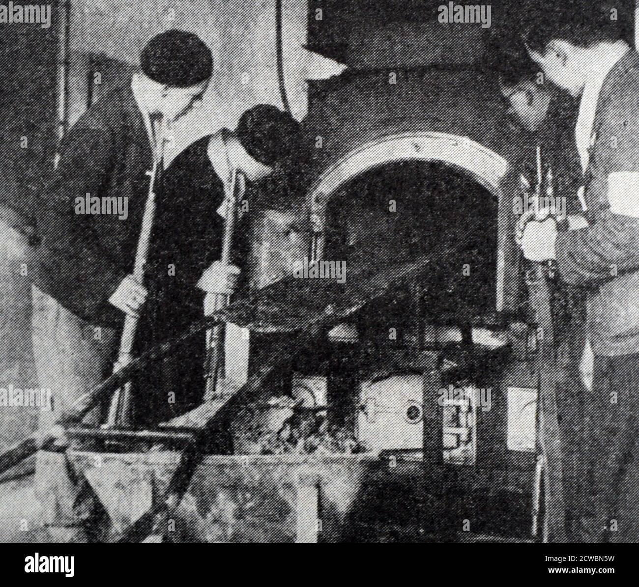 Black and white photograph of World War II (1939-1945) showing the German Concentration Camps at Buchenwald and Struthof; four Allied soldiers inspect one of the ovens used to cremate the remains of executed prisoners. Stock Photo