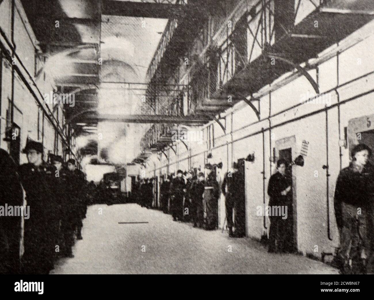 Black and white photograph of World War II (1939-1945) showing images related to the Nuremberg Trials, the largest prosecution in history, and which began in November 1945; a corridor of prison cells with a guard placed at the door of each cell. Stock Photo