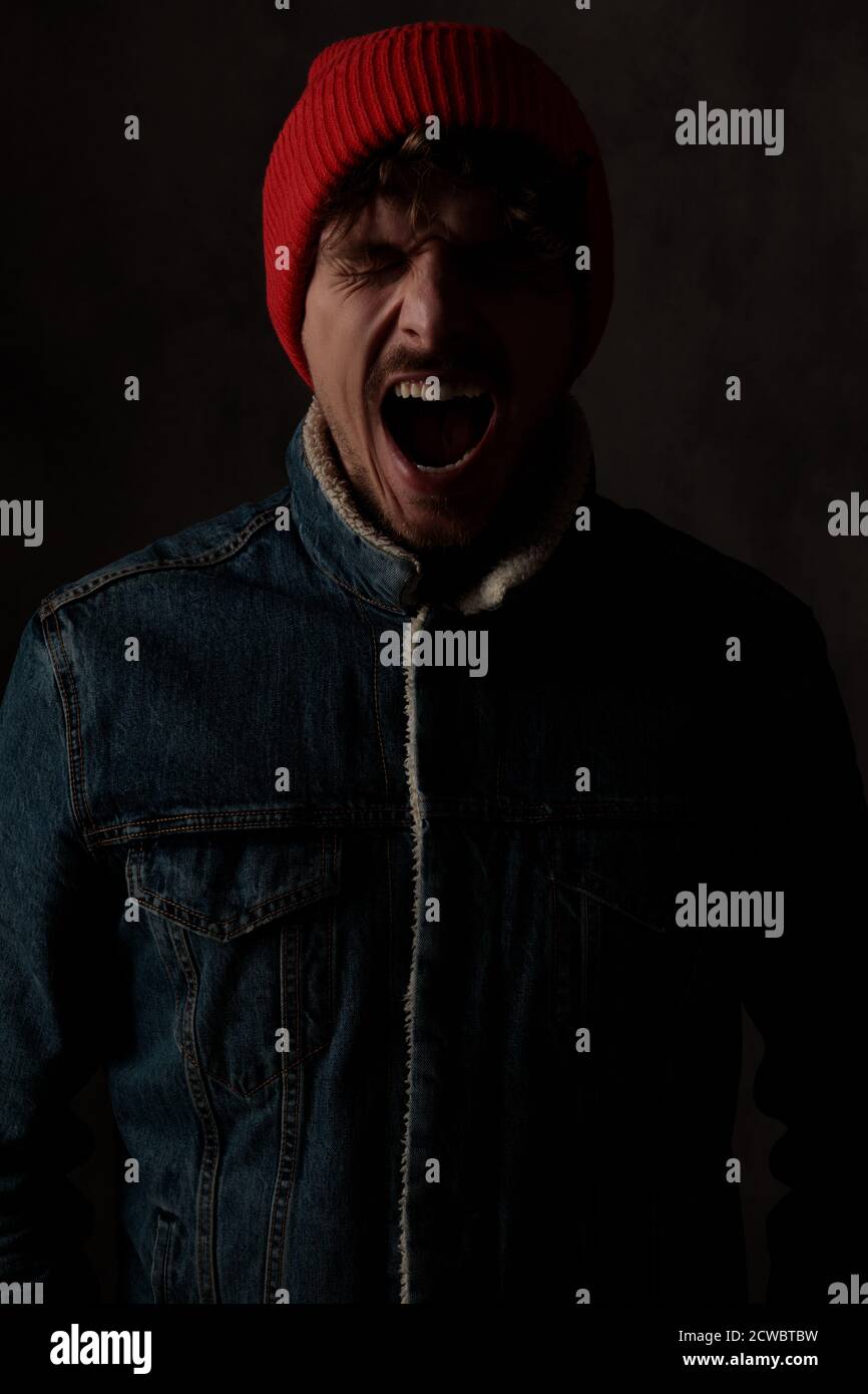 dramatic cool guy wearing red hat and denim jacket, screaming and