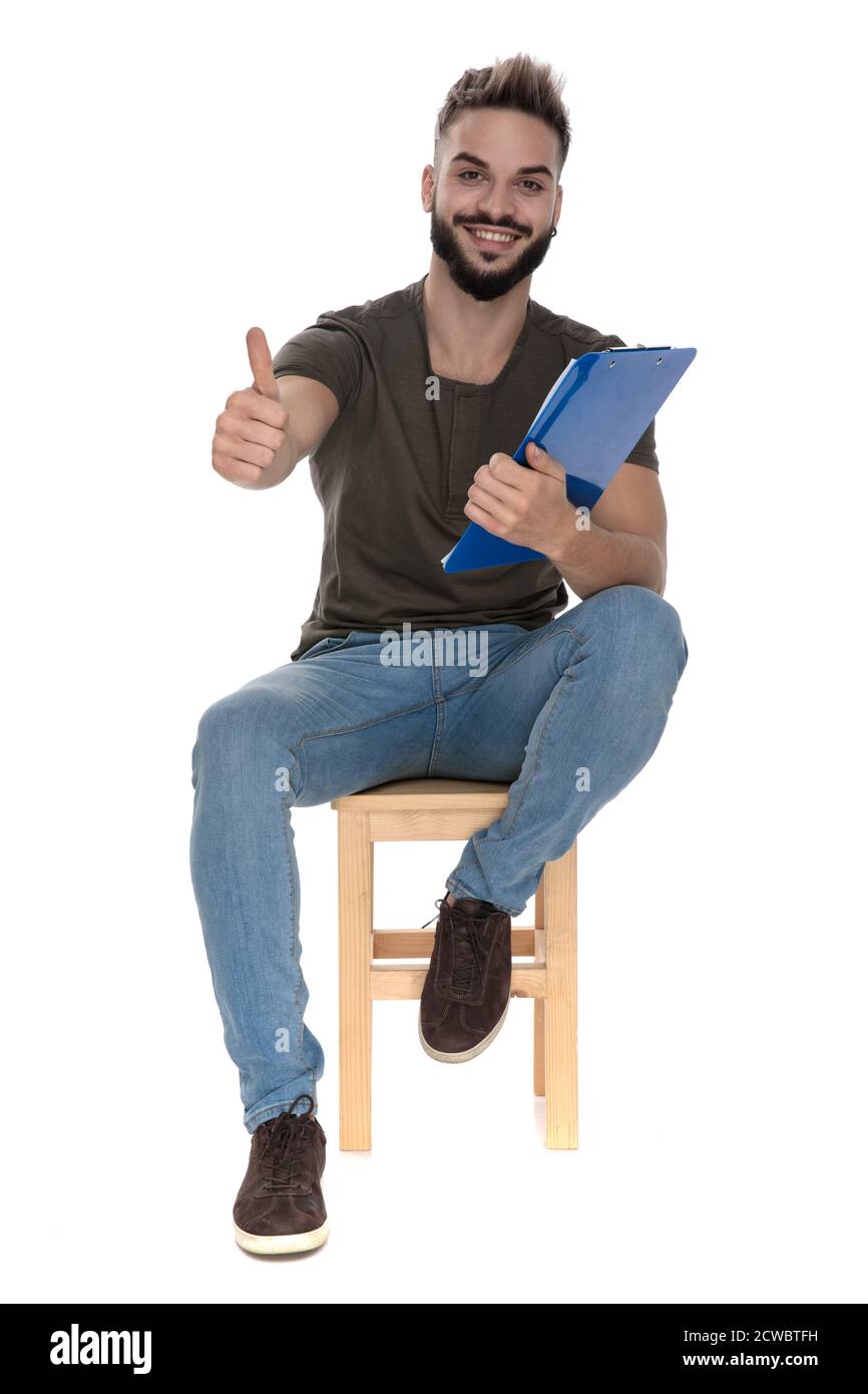 Cheerful student gesturing ok and holding a clipboard with notes while ...