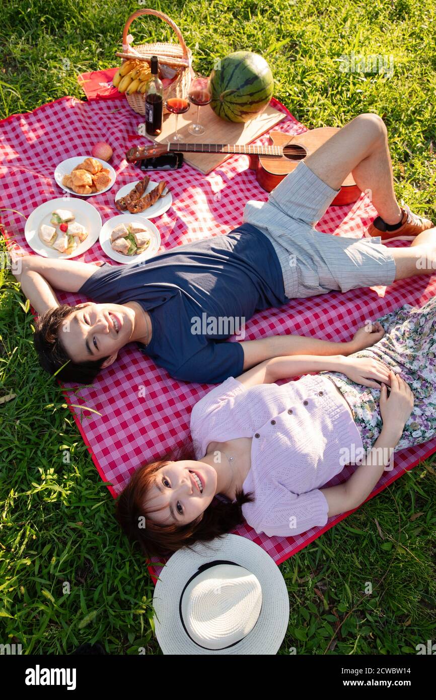 Happy couple lying on the grass Stock Photo - Alamy