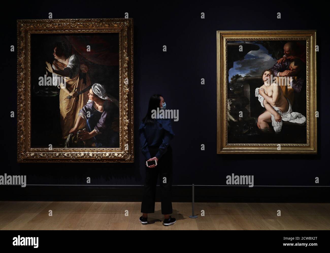 National Gallery staff member Jean Tang poses next to the works (left to  right) Judith and her Maidservant with the Head of Holofernes, about  1623-5, and Susannah and the Elders, 1652, during