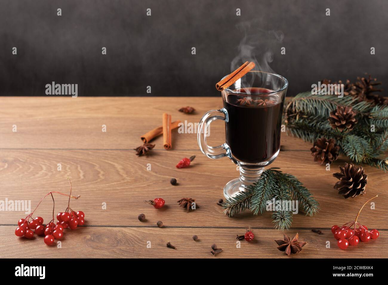 christmas hot mulled wine with cinnamon and anise on wooden background. Traditional Christmas Mulled Wine hot drink with cinnamon stick, red berries a Stock Photo