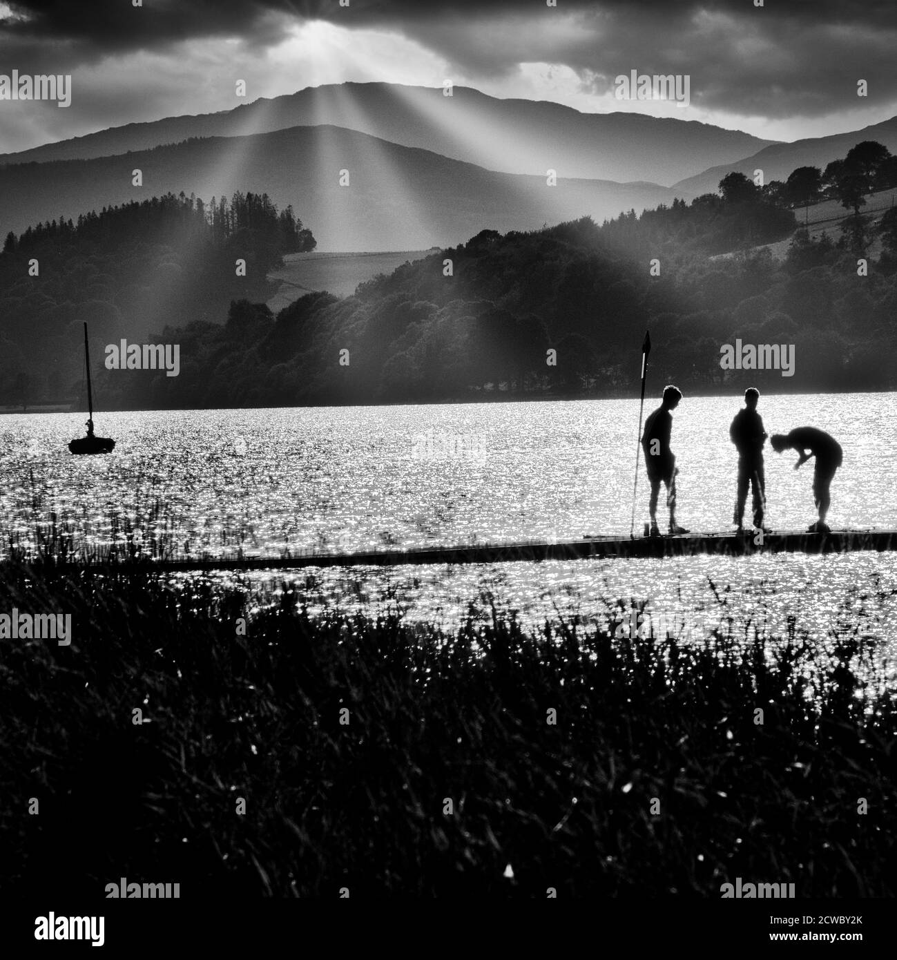 Silhouette of Three boys fishing on North Wales Lake very dramatic Stock Photo