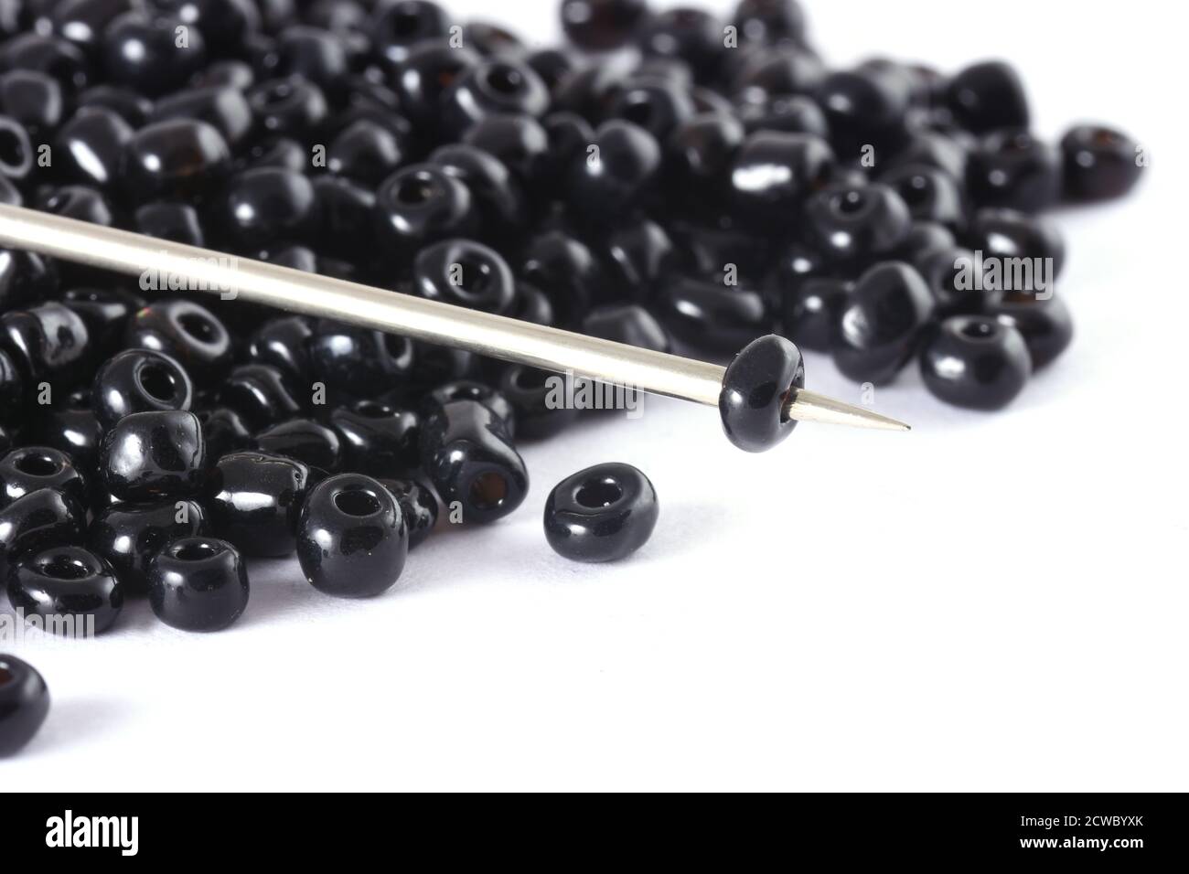Beads spread on white background with needle. Beads with needle . Close up, macro,It is used in finishing fashion clothes. make bead necklace, beads f Stock Photo