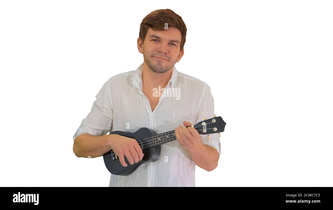 Smiling young man playing ukulele looking into the camera on whi Stock Photo