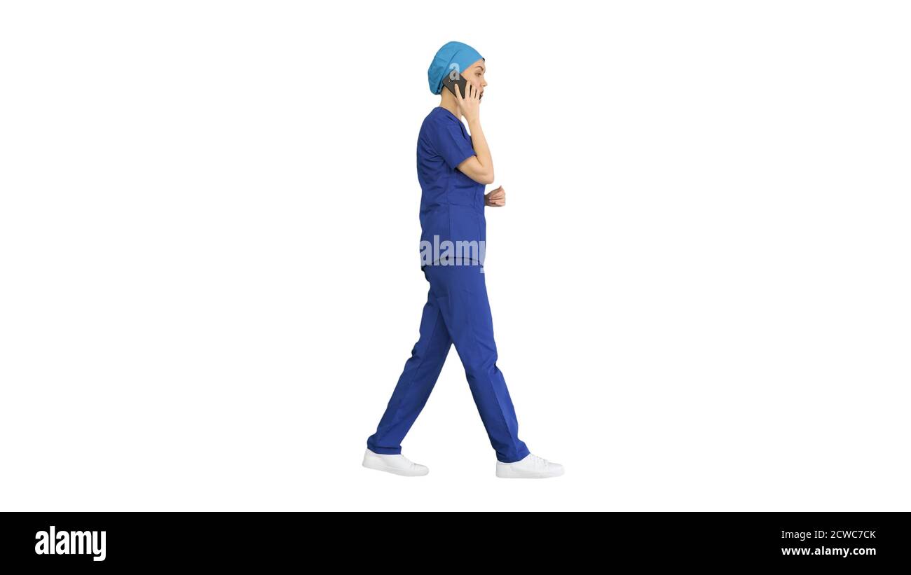 Serious female doctor talking on the phone while walking on whit Stock Photo