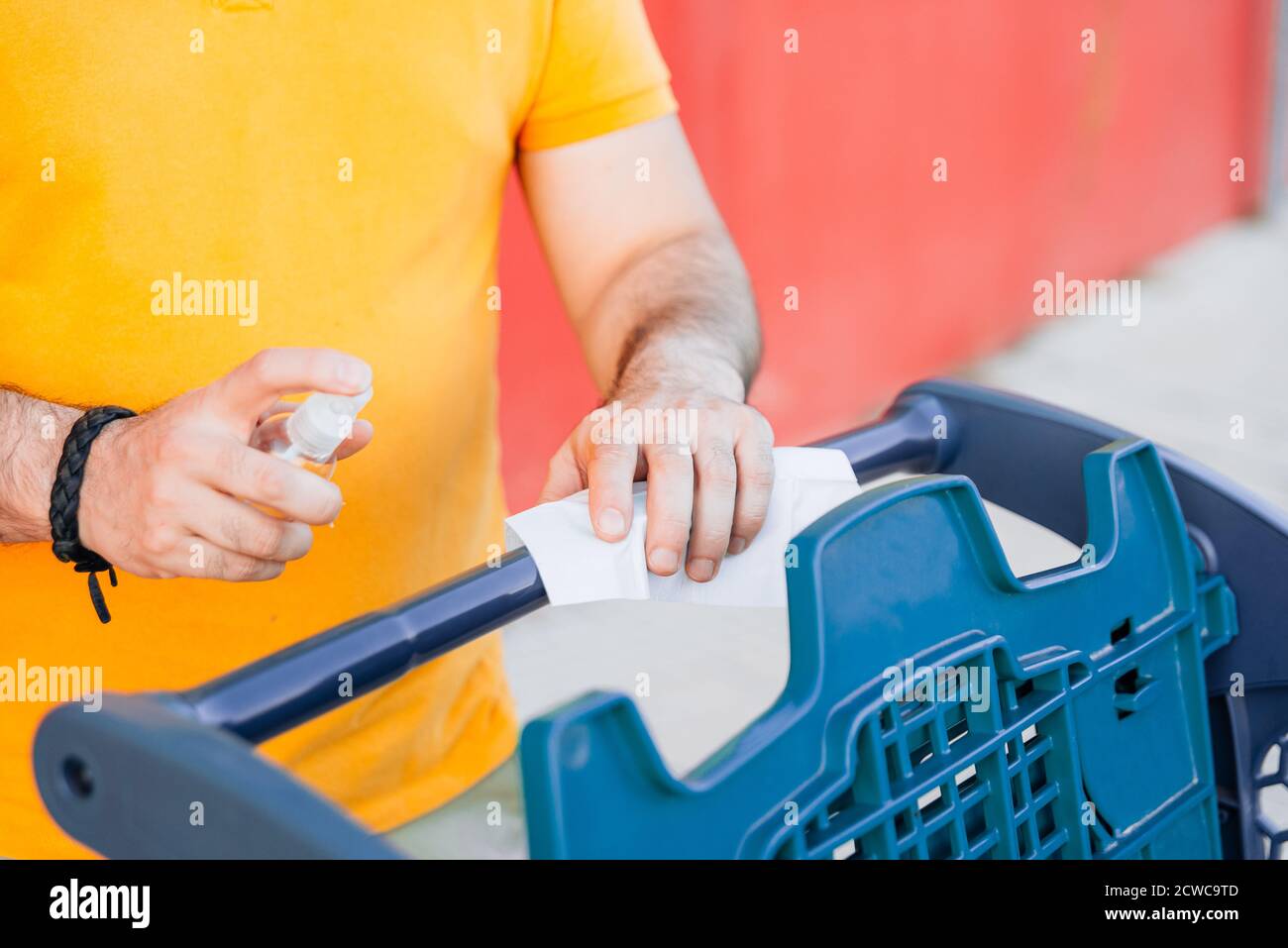 Man cleaning handle of shopping cart using antivirus antibacterial wet wipe. Stock Photo