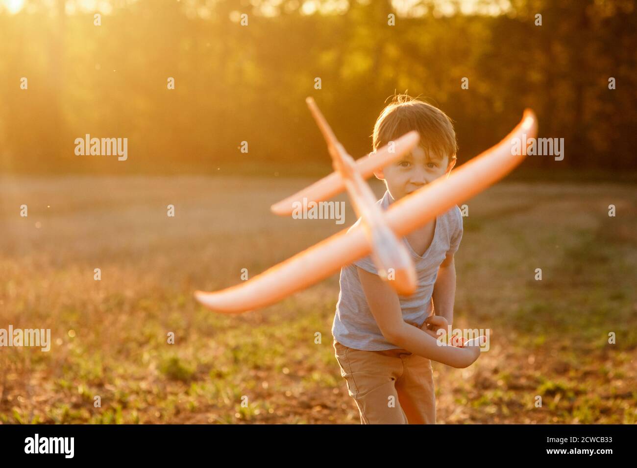 Happy child runs with a toy airplane on a sunset background over a ...