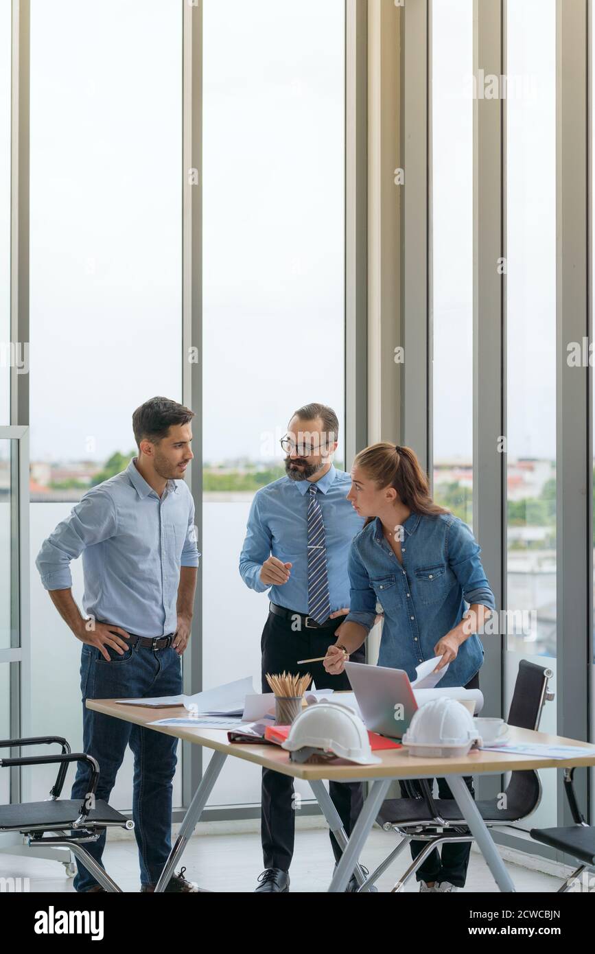 Team of multiethnic architects working on construction plans in meeting room. Engineers discussing on project in office. Stock Photo