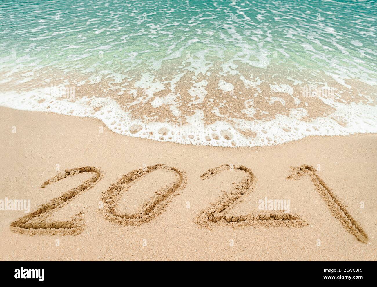 Happy New Year 2021, lettering on the beach with wave and blue sea