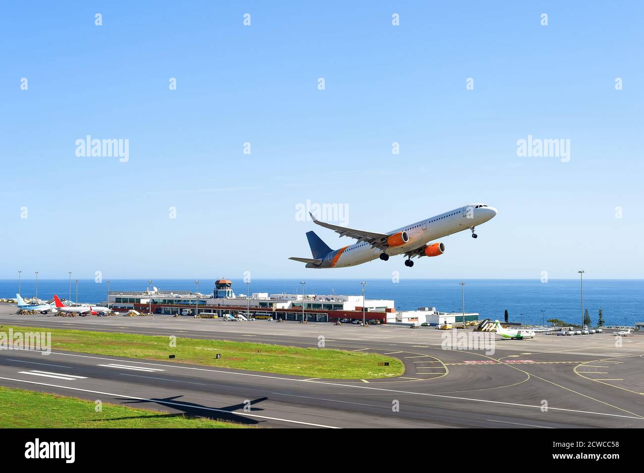 Airplane taking-off, runway of International Funchal airport terminal building, ocean in background, Madeira, Portugal Stock Photo