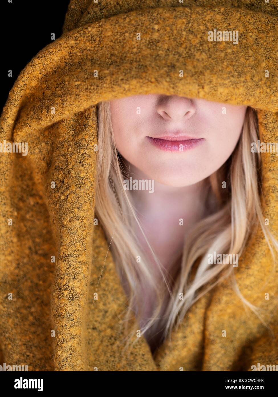Blond woman with yellow hoodie covering part of her face Stock Photo