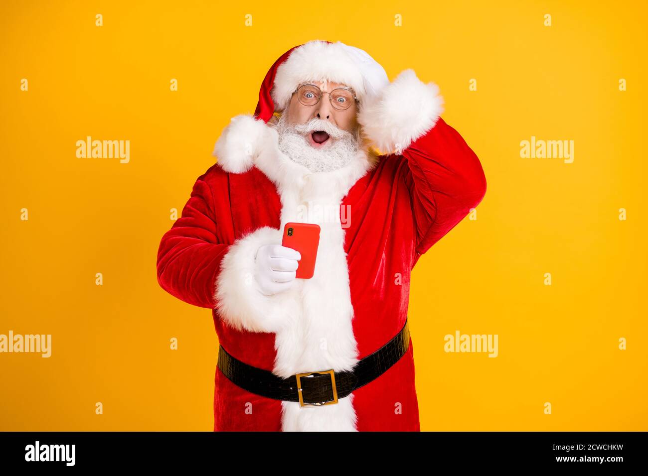 Oh no i send congratulations sms wrong x-mas christmas party. Amazed grey beard santa claus use smartphone touch cap hand wear red style costume Stock Photo