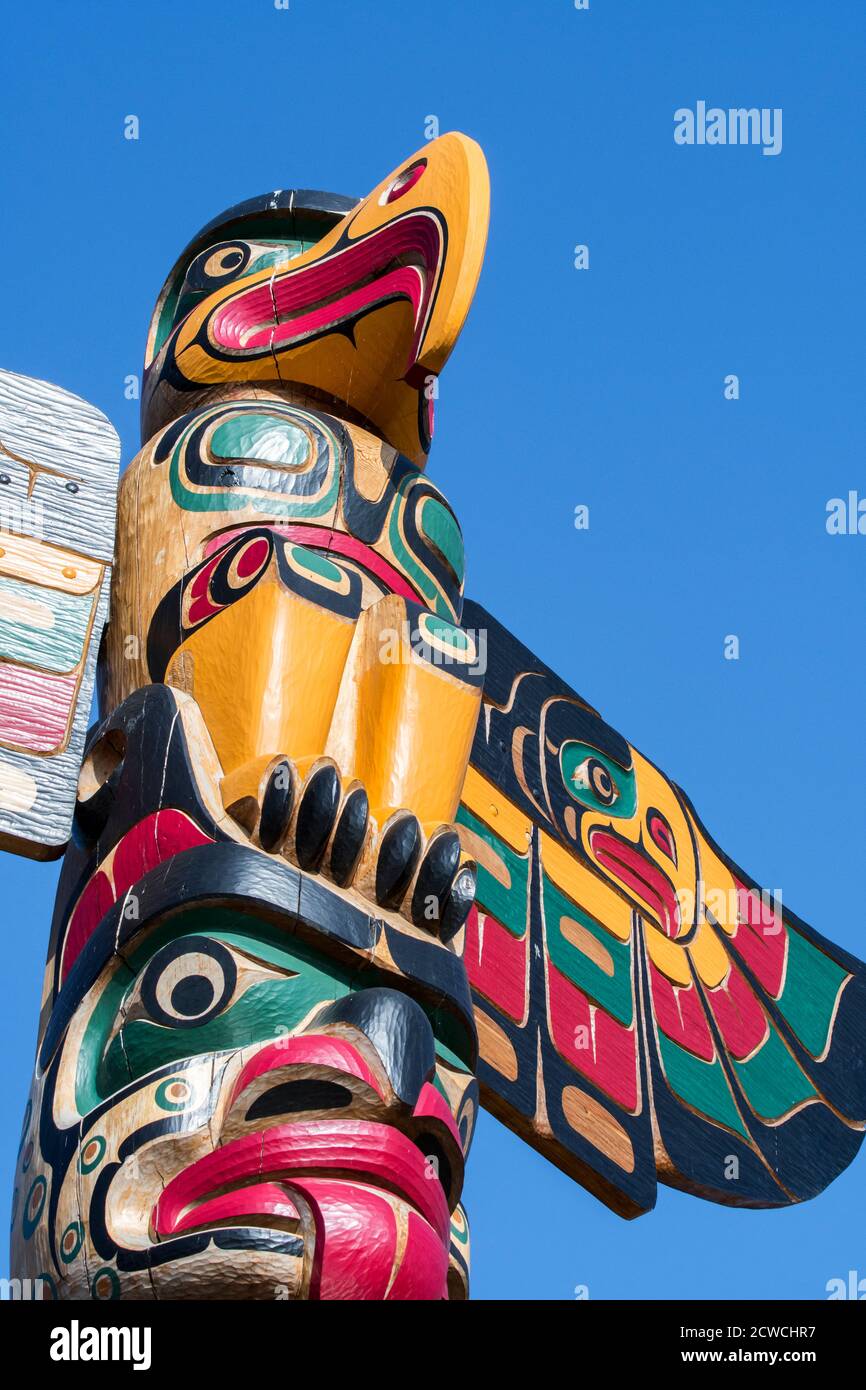 Colourful wooden carved Canadian totem pole showing eagle against blue sky Stock Photo