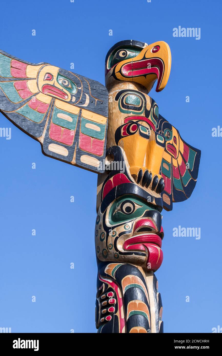 Colourful wooden carved Canadian totem pole showing eagle against blue sky Stock Photo