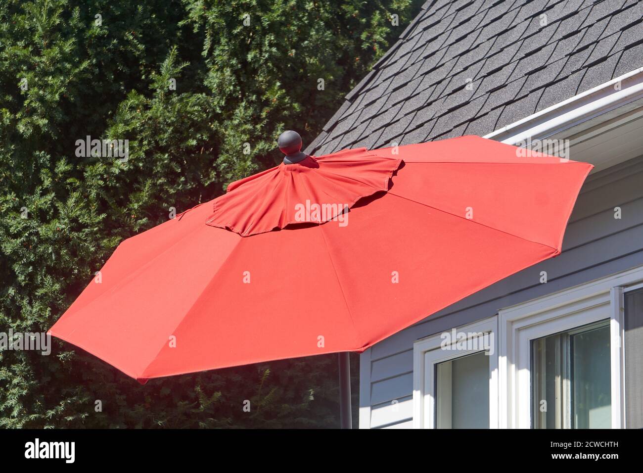 Big red outdoor umbrella outside a house Stock Photo