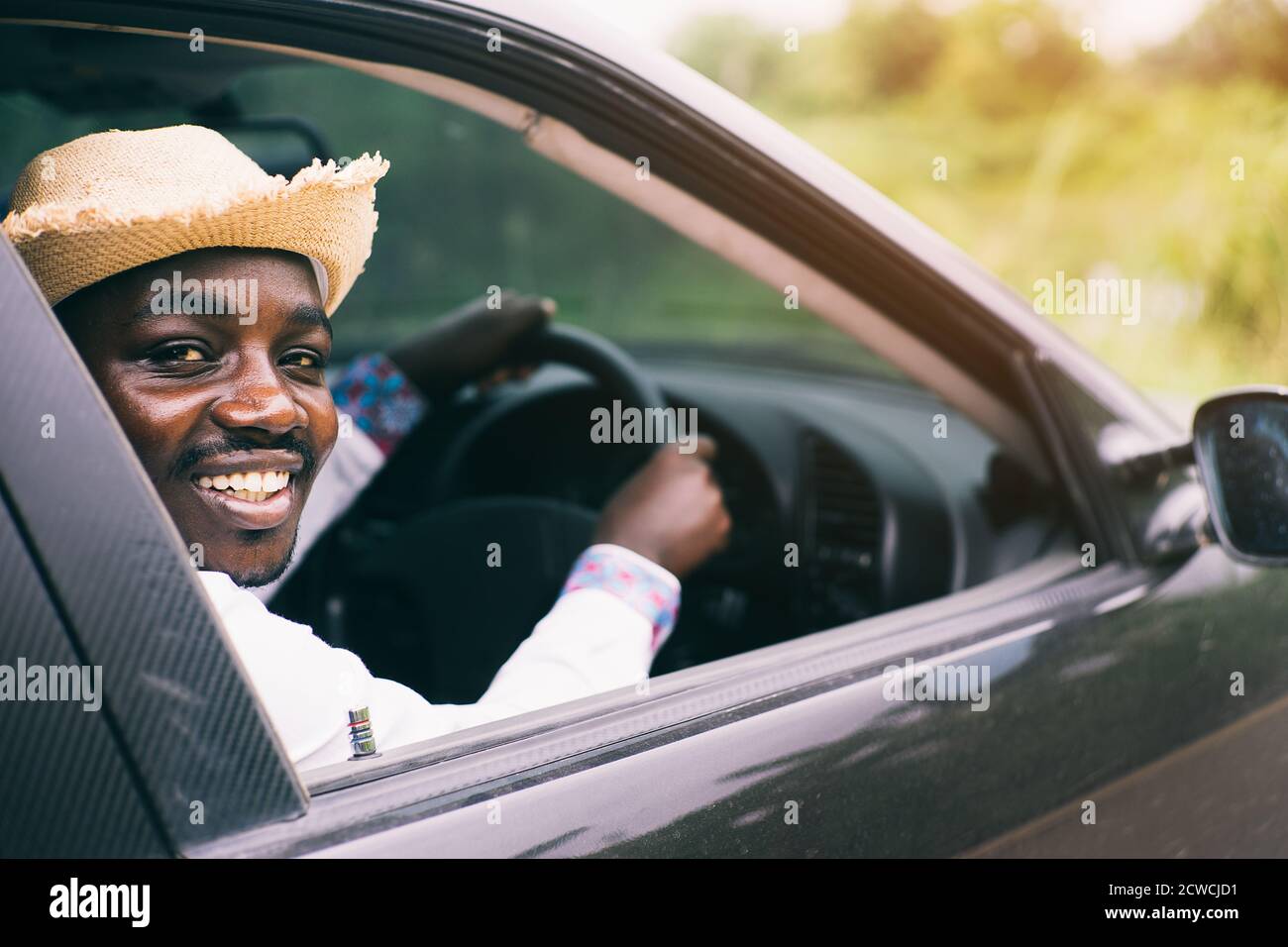 African man driver wearing a hat and smiling while sitting in a car