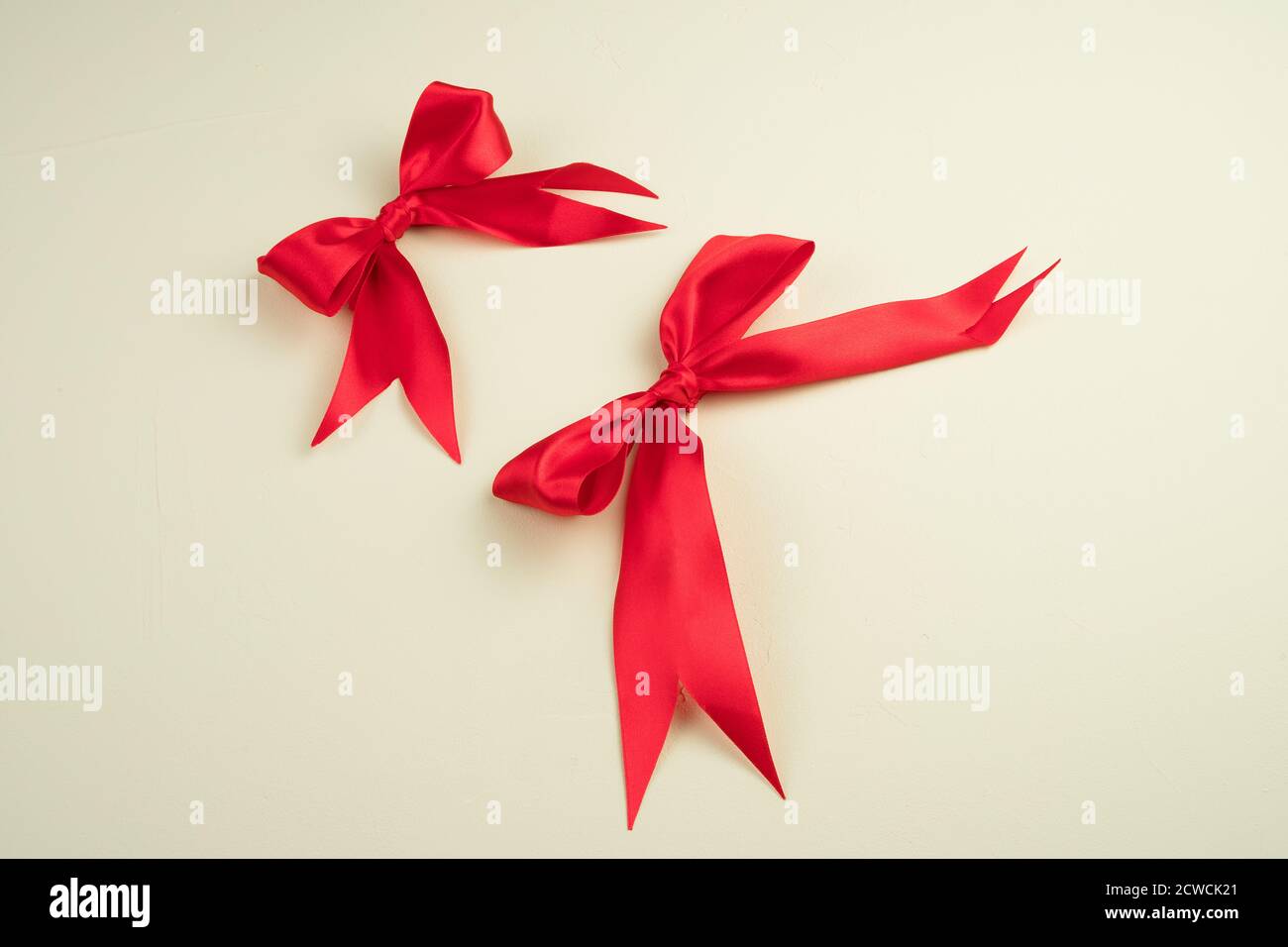 Red satin bows on a light beige background. Stock Photo