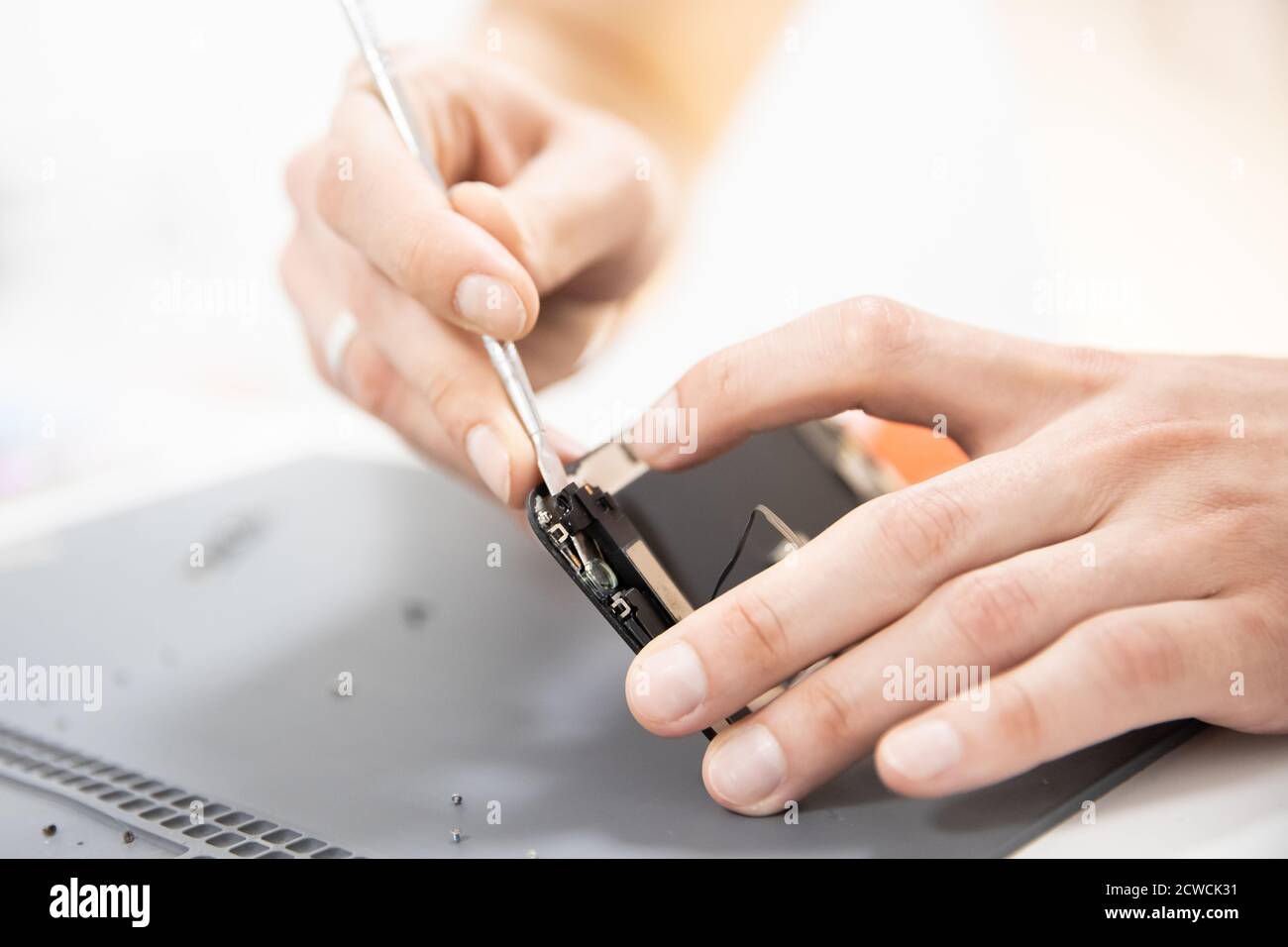 Master disassembles modern mobile phone, repairs and replaces battery, broken screen Stock Photo