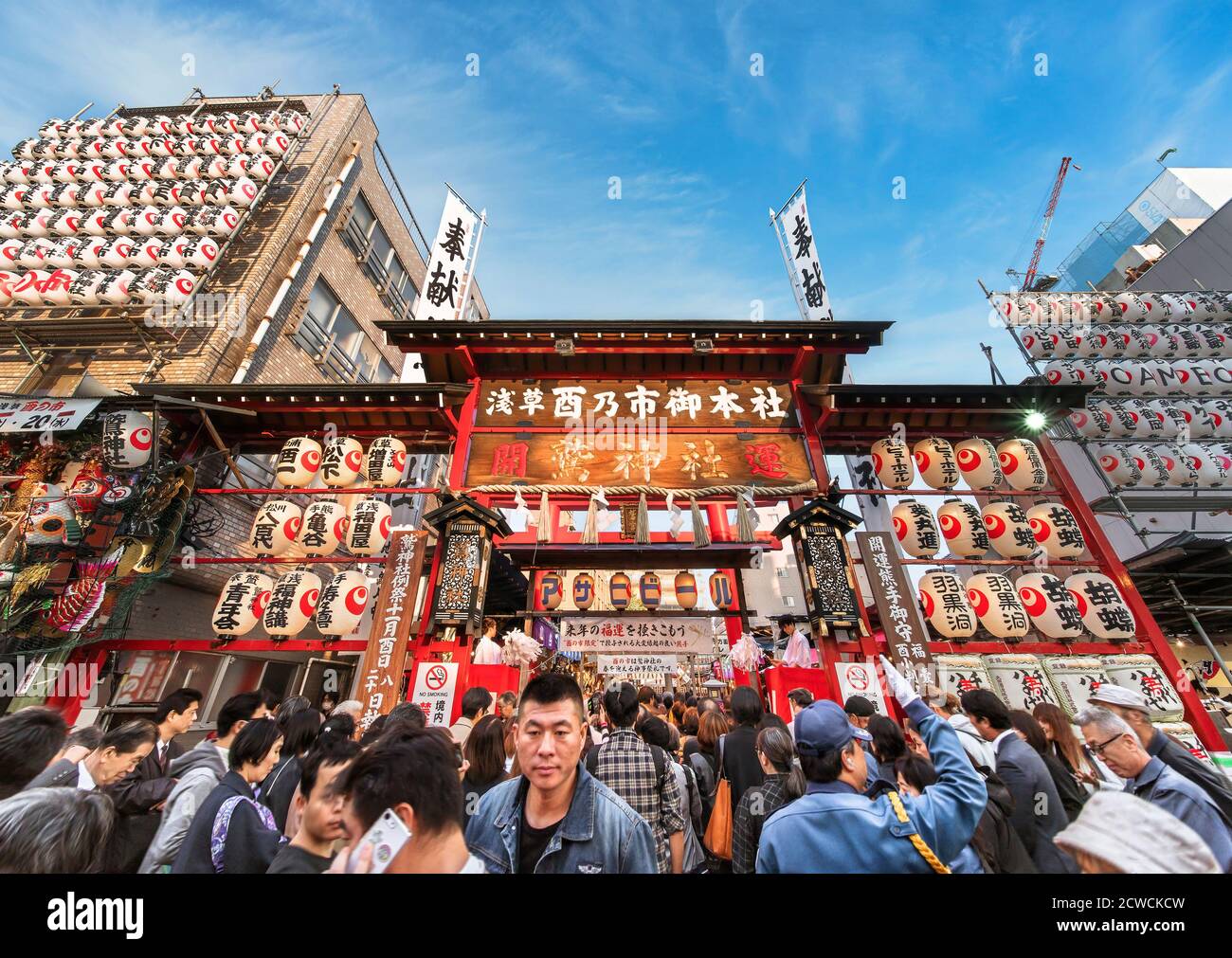 akihabara, japan - november 08 2019: Crowds agglutinated at the  gate of the Ootori shrine decorated with paper lanterns to buy auspicious bamboo rake Stock Photo