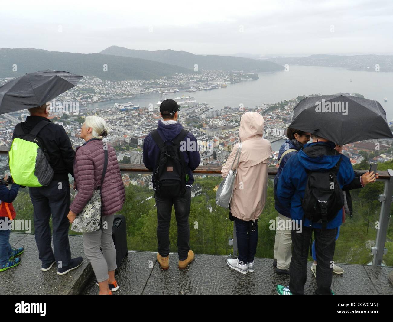 Tourists in colourful jackets are admiring the view of Bergen in light rain Stock Photo