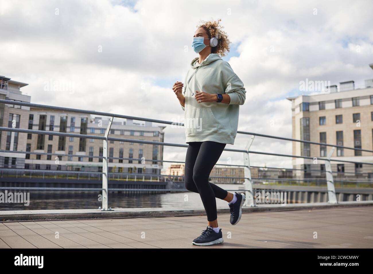 Young healthy woman in protective mask jogging in the city Stock Photo ...
