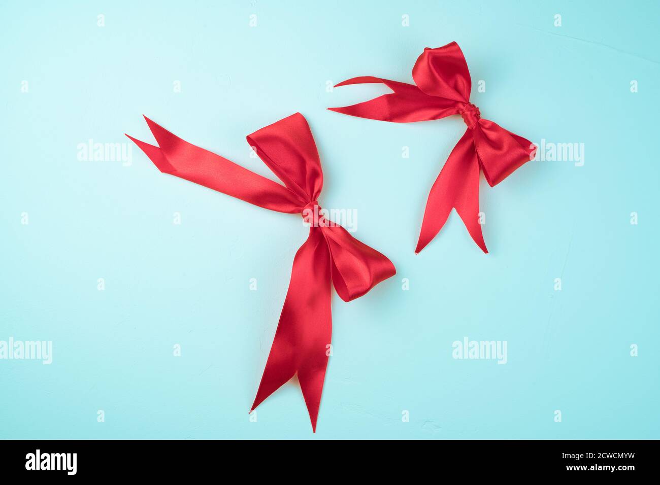 Two Red satin bows on a light blue background. Stock Photo