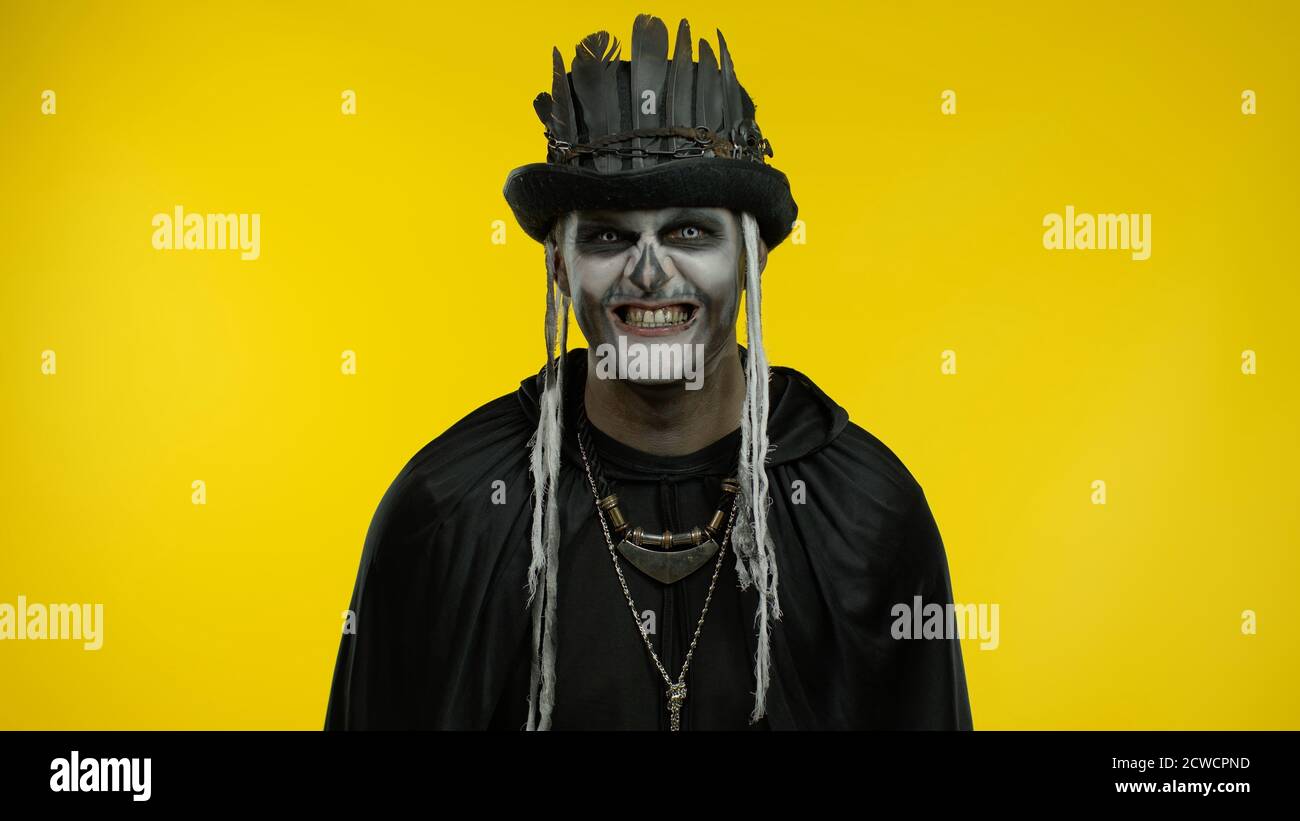 Sinister man with horrible Halloween skeleton makeup in costume with top-hat  making faces, looking at camera trying to scare. Horror theme. Day of The  Dead. Yellow background. Copy space Stock Photo -