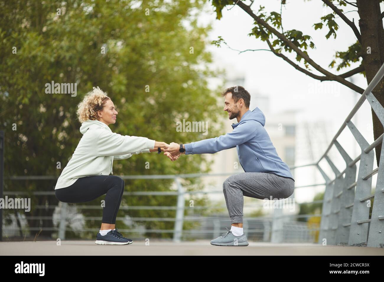 Young healthy couple holding hands and exercising during training in the park Stock Photo