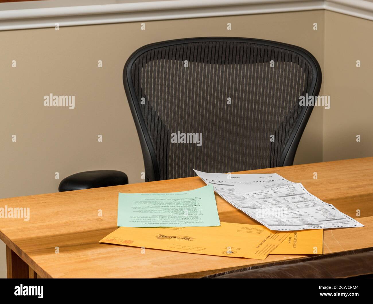 Empty home desk and chair with paperwork for completing the mail-in or absentee ballot for the 2020 presidential election Stock Photo