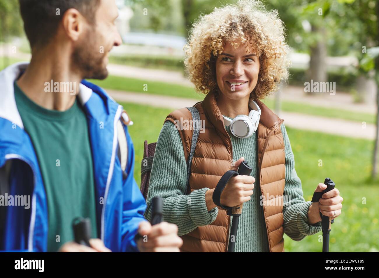 Young happy woman smiling and talking to young man during their sport walking in the park Stock Photo