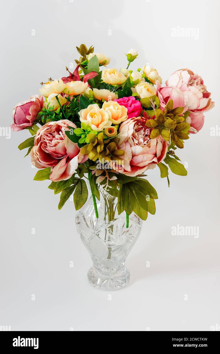 a bouquet of colorful flowers in an ornate crystal vase, against a bright background Stock Photo