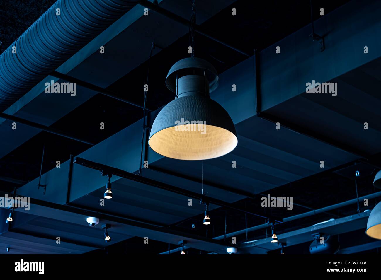 Selective focus. Black lamp hanging from the ceiling. Interior decoration of stylish bar. Modern style design. Black background Stock Photo