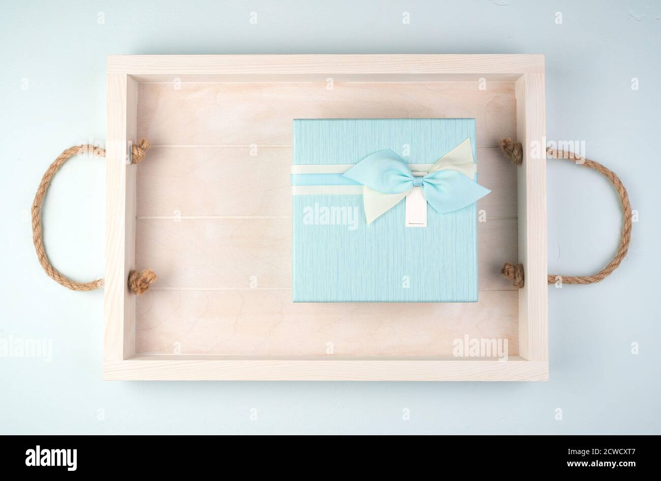 Soft blue gift box with a bow on a white tray. Stock Photo