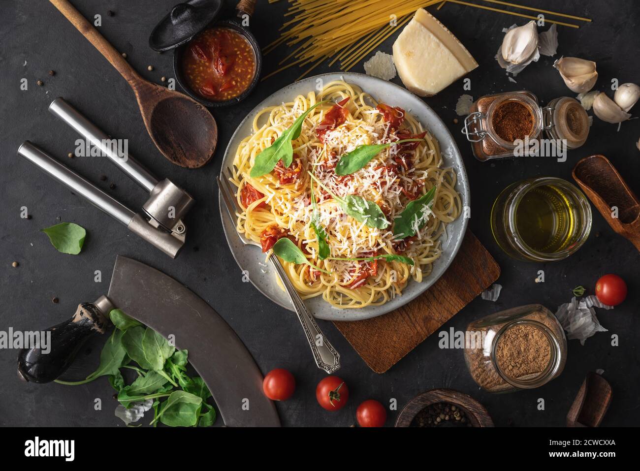 Italian dinner with pasta on ceramic plate with ingredients around on black background. Flat view. Top view. Stock Photo