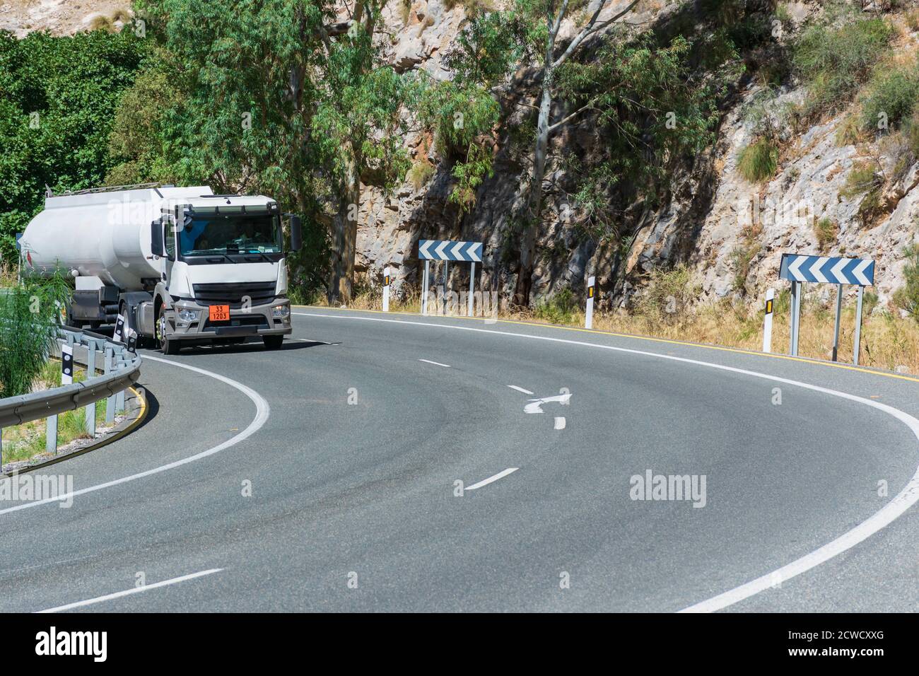 Fuel tank truck driving around a curve in the road Stock Photo