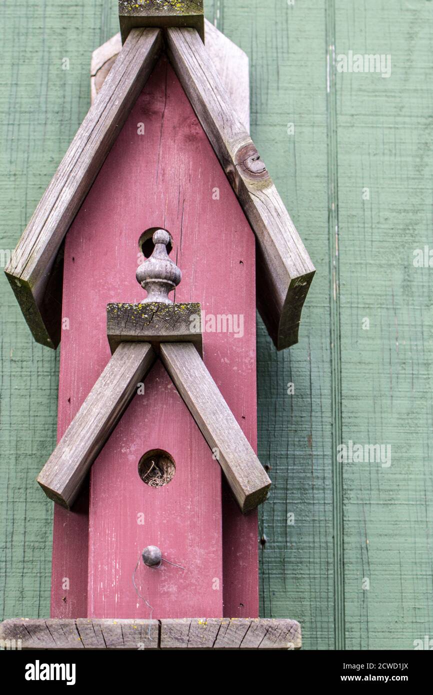 Rustic barn red wooden birdhouse in vertical orientation. Stock Photo