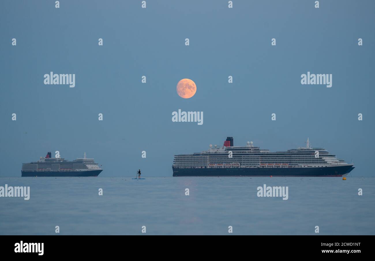 Weymouth Bay, Dorset, UK. 29th September, 2020. UK Weather. A lone paddle boarder watches the near full moon rise behind the Cunards Covid 19 hit crusie ships. Credit: DTNews/Alamy Live Stock Photo