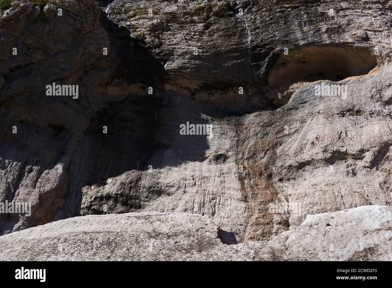 rock wall with niche with streams of water flowing down it over the melting glacier in the mountains Stock Photo
