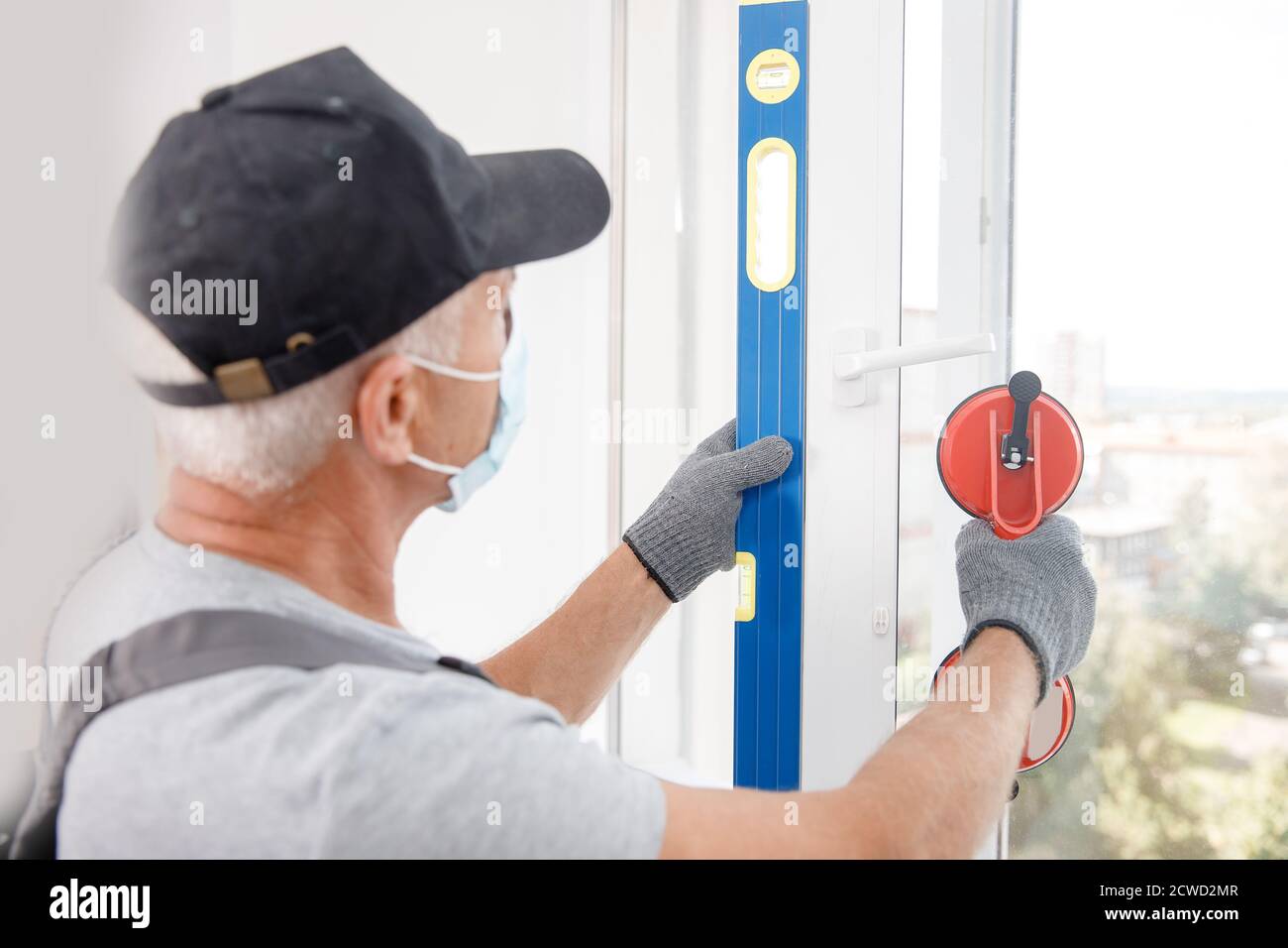 Worker man in medical mask installs plastic upvc windows and doors ...